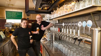 Tjark-Peter Maaß und Dominique Schilk stehen vor der Zapfanlage ihres Restaurants