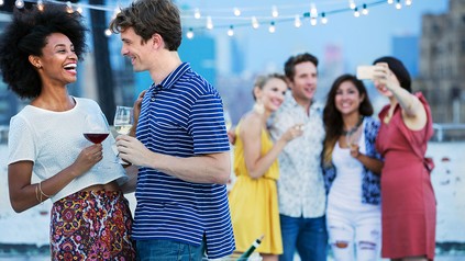 Junge Menschen stoßen im Freien mit Wein an und Feiern