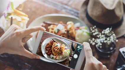 Eine Frau fotografiert ein Gericht mit einem Handy