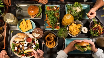 Peter Pane, gedeckter Tisch mit zahlreichen Speisen von Pommes über Salat bis hin zum Burger. (Foto: © Peter Pane)