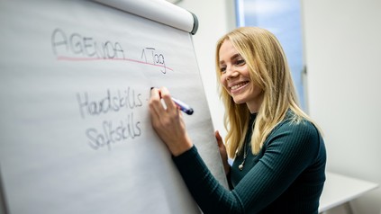 Frau steht an einem Whiteboard und notiert eine Agenda für ein Modul