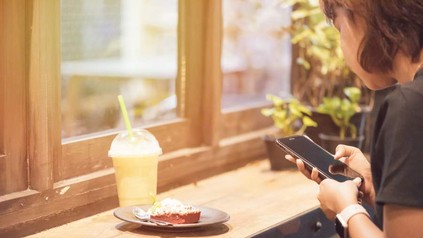 Frau mit Smartphone vor Dessert