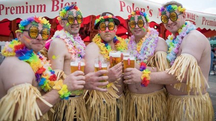 Englische Touristen mit Baströcken und bunten Blumenketten beim Trinken des Zywiec Bieres