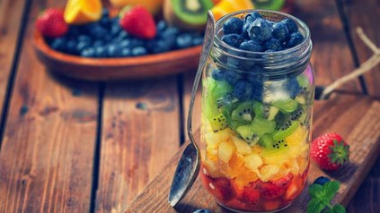 Ein Glas mit Erdbeeren, Orangen, Ananas, Kiwi und Blaubeeren