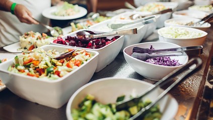 Schüsseln mit Salaten und verschiedenem Gemüse bei einem Büfett in einer Kantine