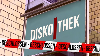 Schild mit dem Schriftzug "Diskothek" und ein rot-weißes Absperrband auf dem "geschlossen" steht