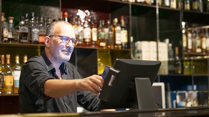 Barkeeper oder Gastronom bedient eine elektronische Registrierkasse