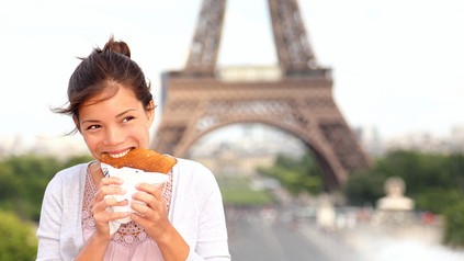 Kind isst Crepe vor dem Eiffelturm in Paris