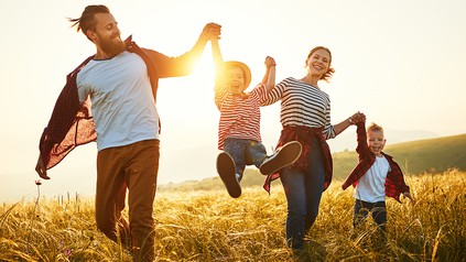 Familie läuft lachend über Wiese