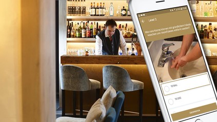 Ein Barkeeper im Hintergrund, ein Handy mit Lern-App im Vordergrund