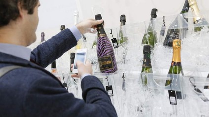 Ein Mann Fotografiert im Rahmen der Champagner-Lounge eine Flasche Champagner